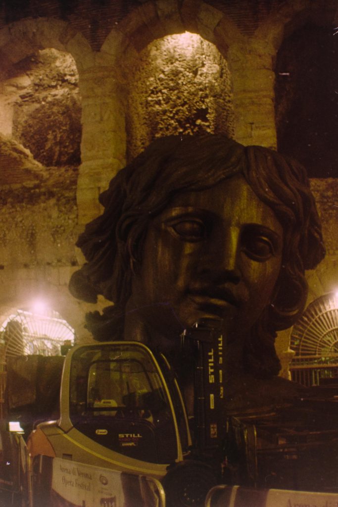 a giant head used as a prop for the Aida show, sitting in front of the Arena of Verona with a forklift in front of it