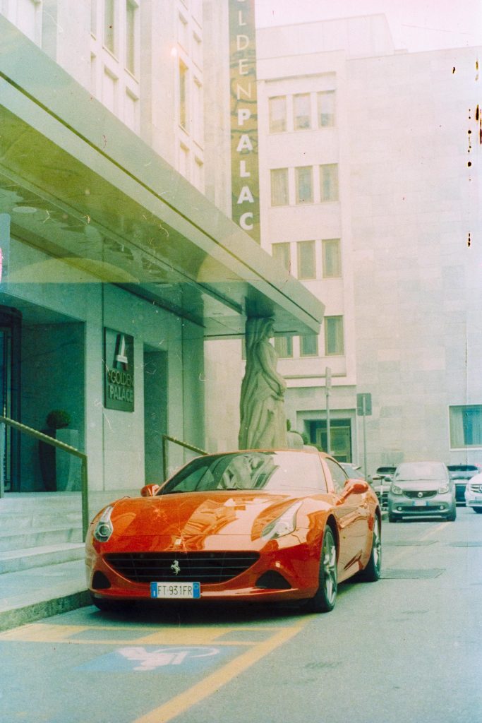 A red Ferrari car parked in front of an hotel