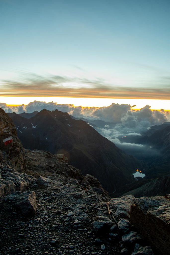 A mountain lake seen at sunrise in the distance from a mountain top