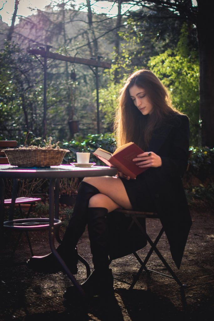 A well-dressed girl reading in a garden
